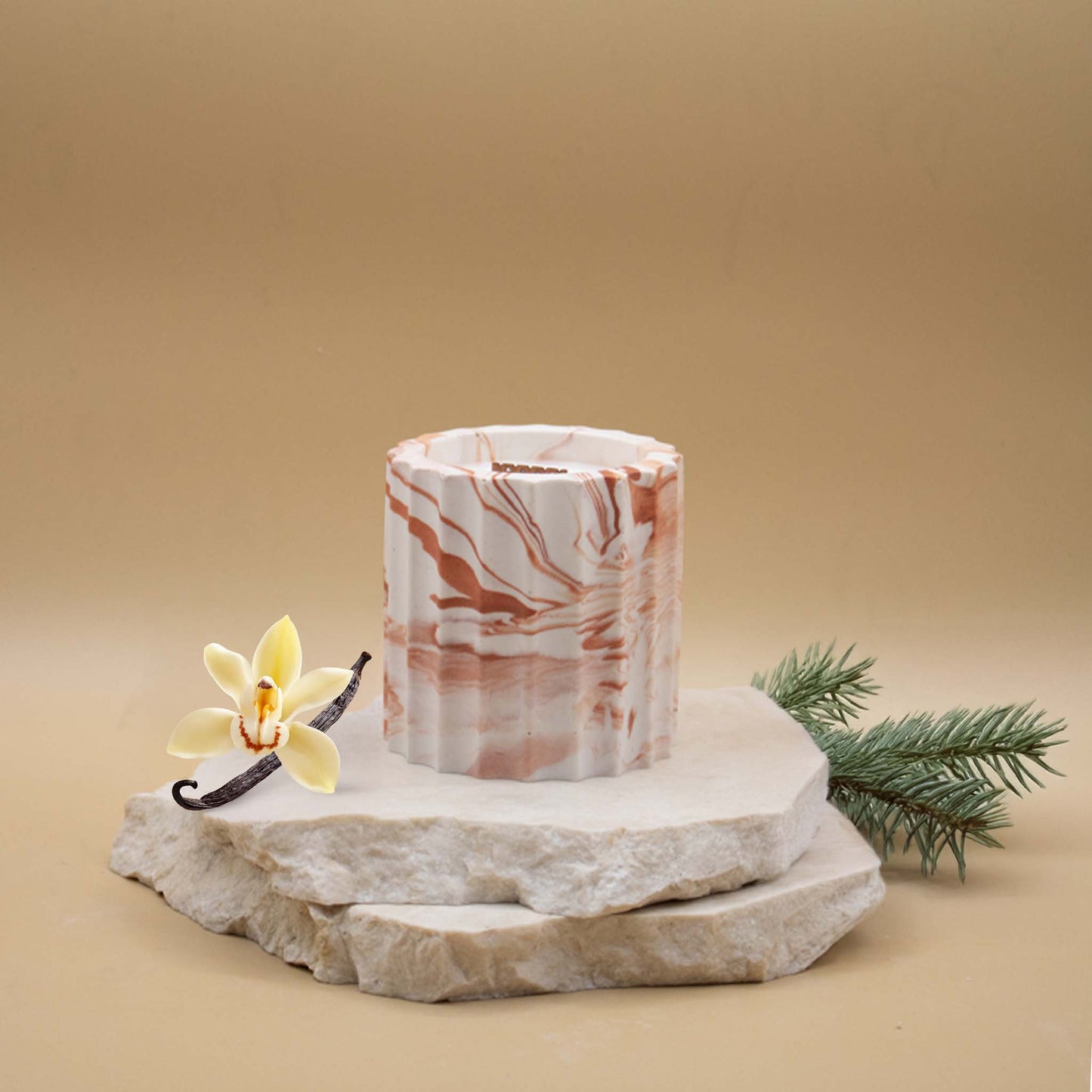 Bougie artisanale marbrée dans des tons de blanc et de terracotta en forme de colonne romaine, posée sur une pierre naturelle, accompagnée d'éléments évoquant la vanille boisée, sur un fond beige.